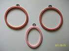 THREE PINK RUBBER AND PLASTIC FRAMING HOOPS W/ HANGERS
